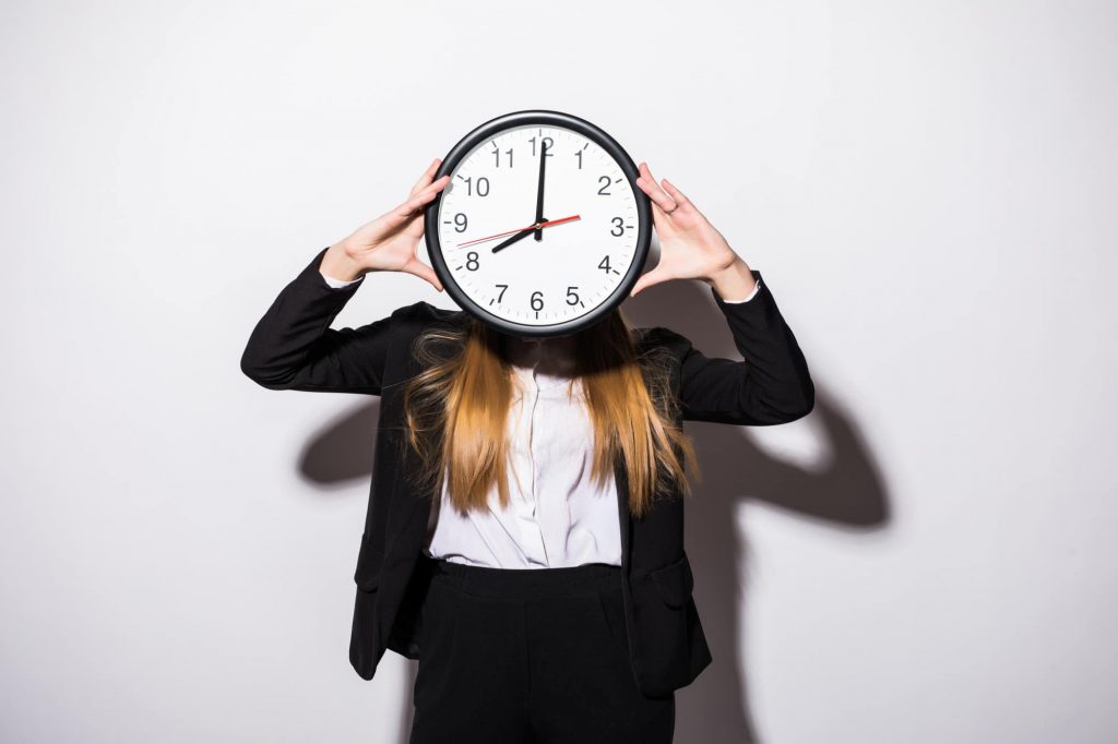 Environnement de travail flexible : une jeune femme d'affaires tenant une horloge devant son visage 